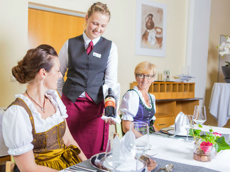 Eine Frau schenkt einem Gast Wein ein